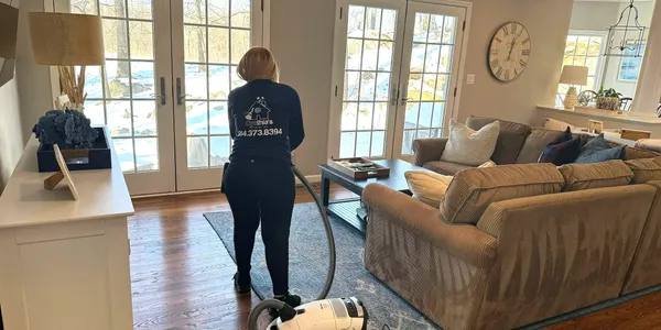Vacuuming a living room rug during routine maintenance cleaning